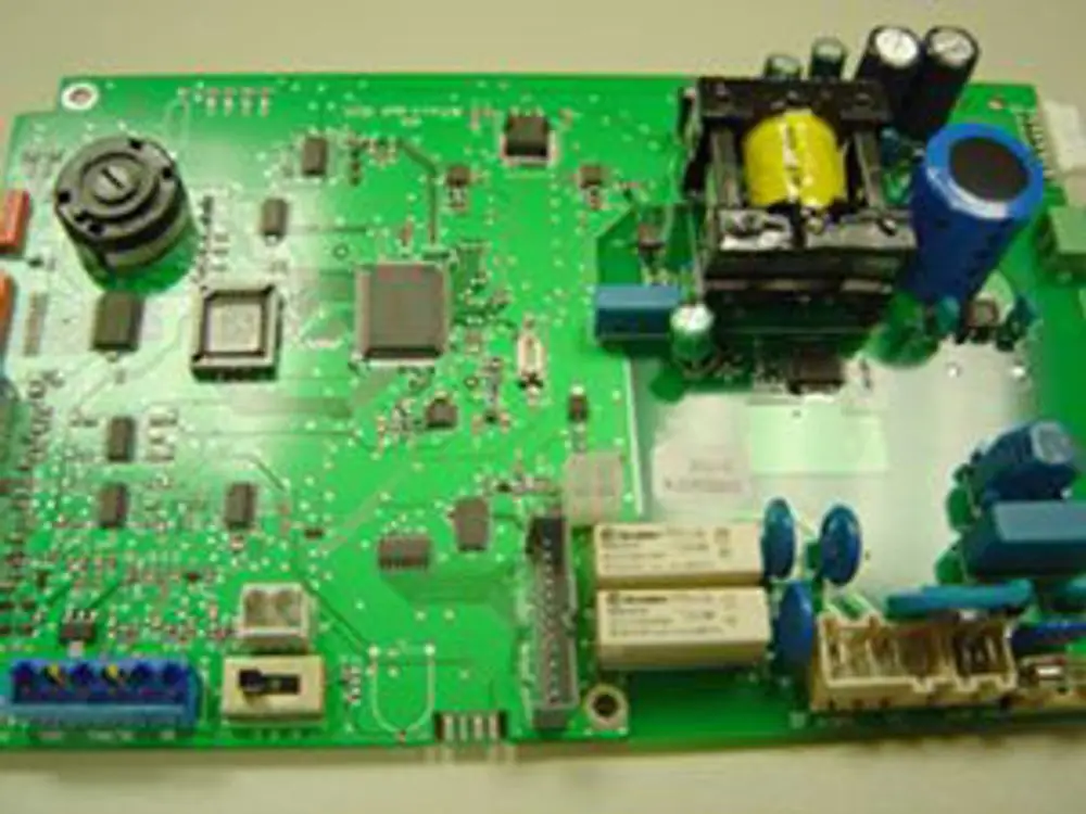 Grüne elektronische Leiterplatte mit verschiedenen Bauteilen, darunter ein Transformator und Kondensatoren, hergestellt von Remeha.